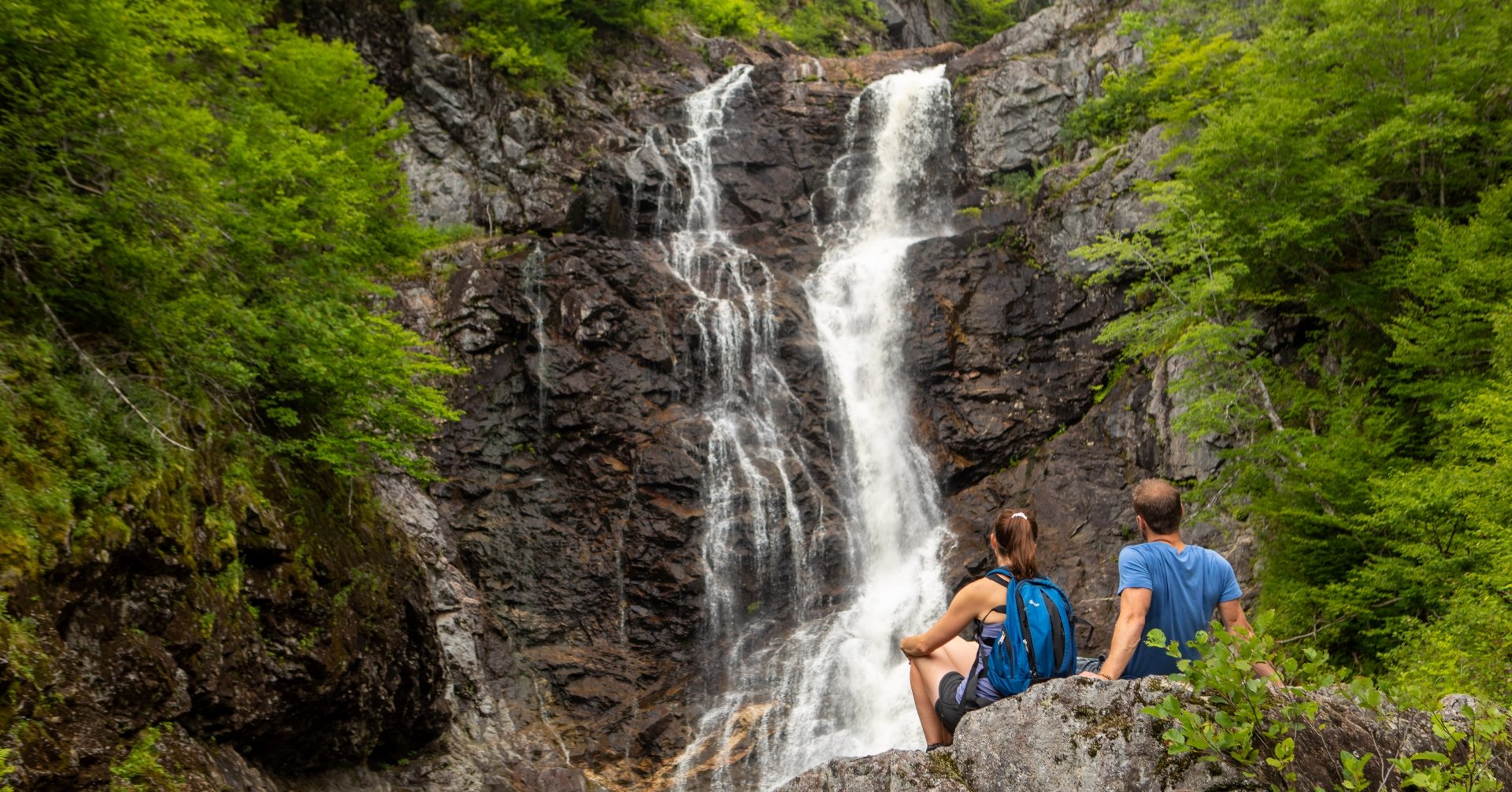 couple sits admiring rocky waterfall