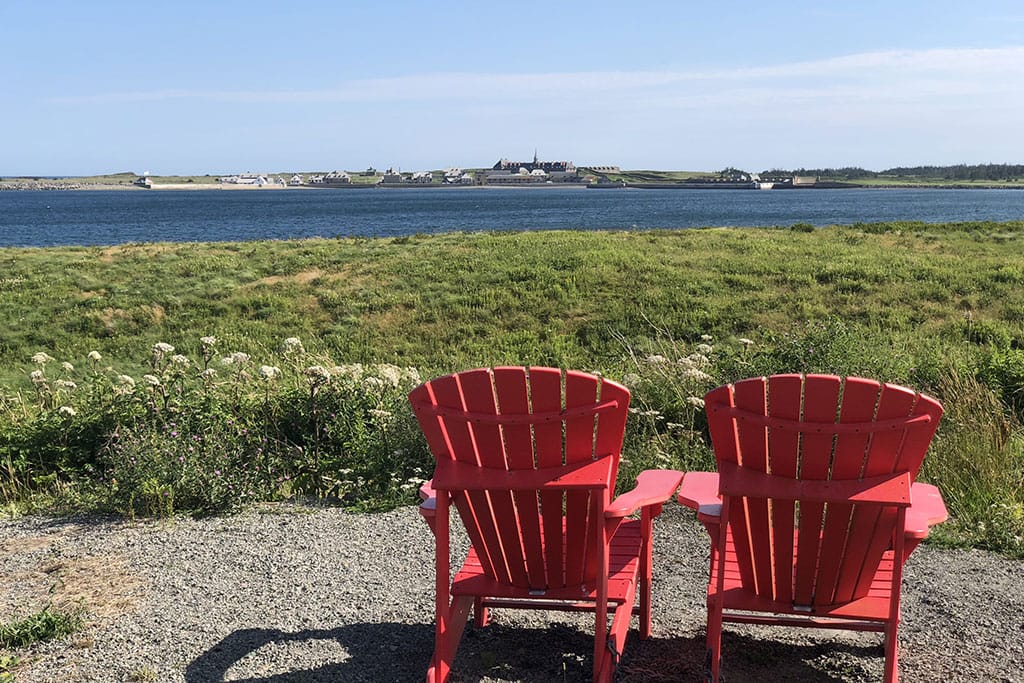 Two adirondack chairs overlook the ocean