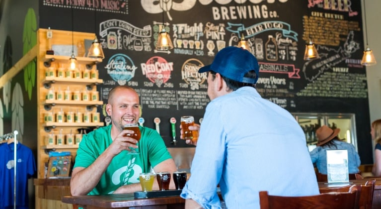 two men sit at a table enjoying beer