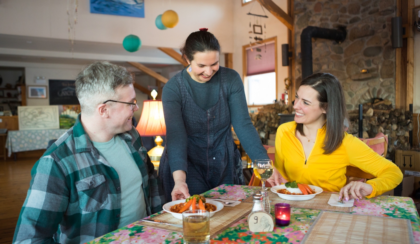 waitress brings two plates of food to a couple at a table