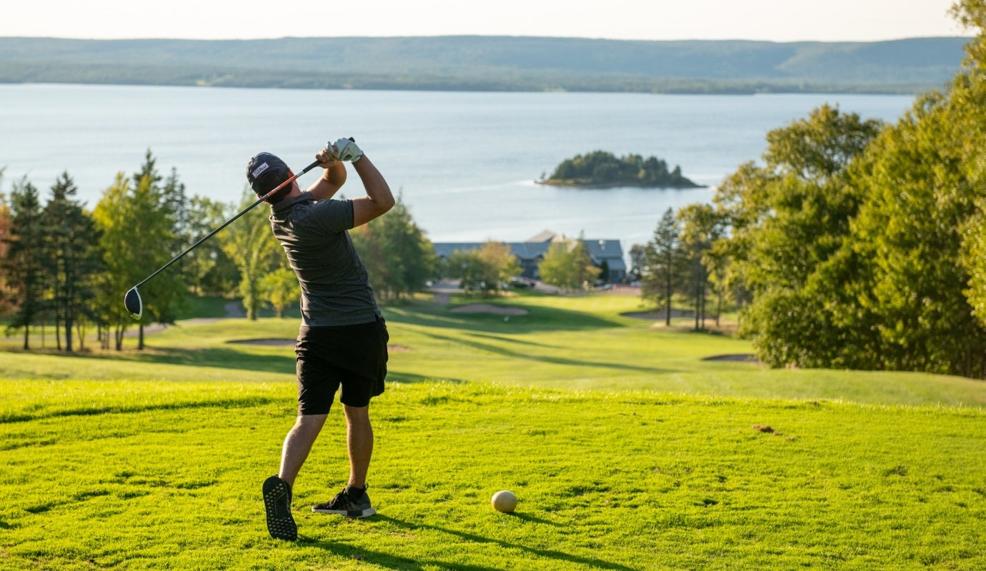 golfer makes a shot by the ocean on cape breton island